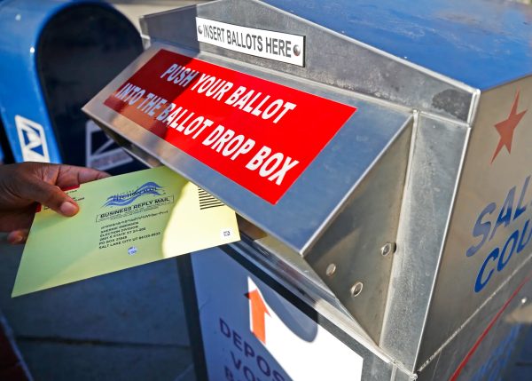 Voters drop mail-in-ballots into ballot boxes. (Source: George Frey)