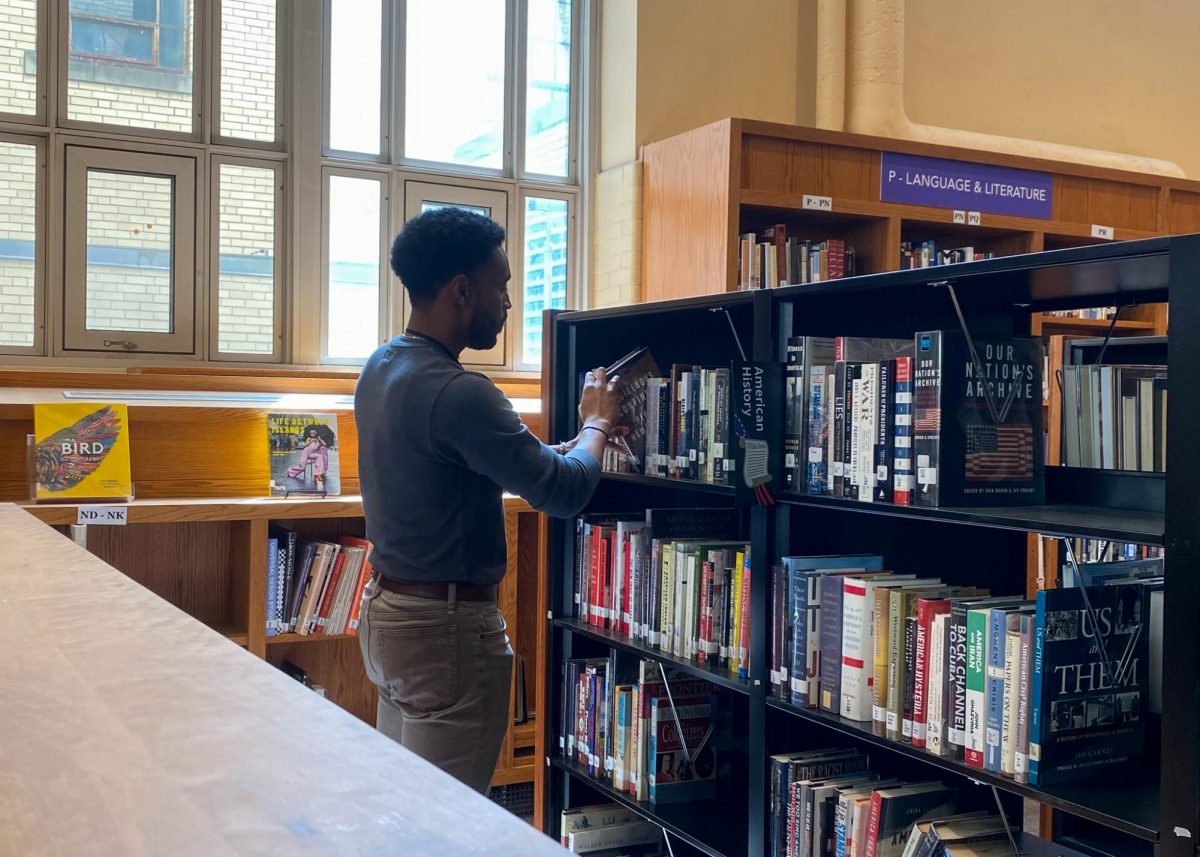 Intern Mr. Phil Whitney browses the Keefe Library. (Source: Sebastian Araujo (IV))